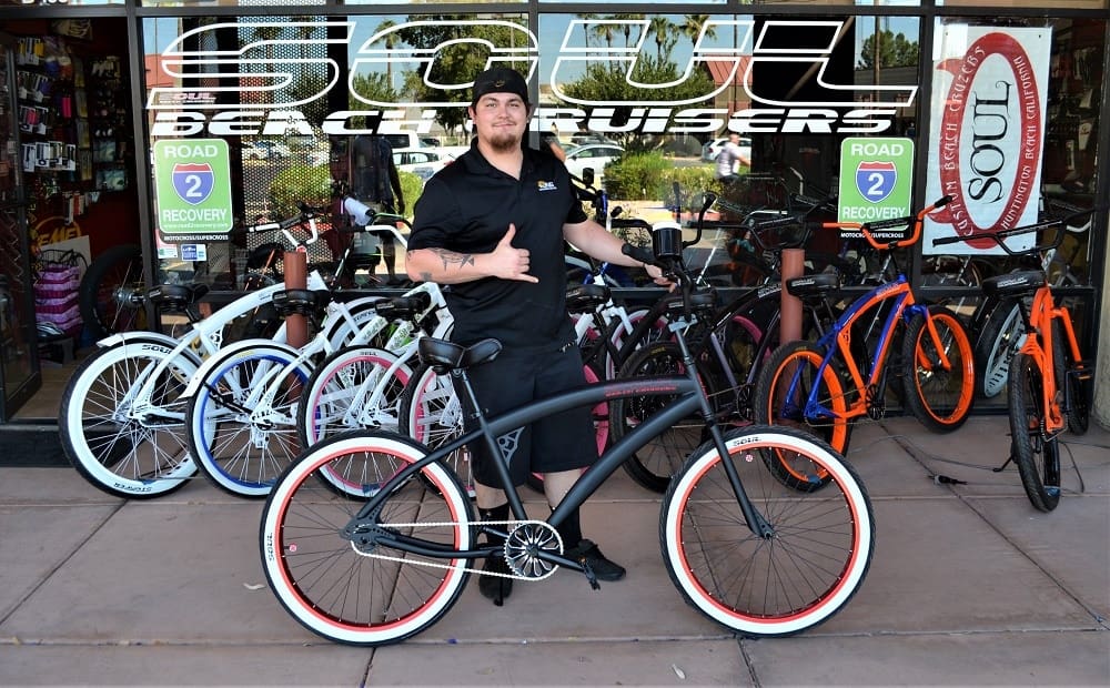 Man posing with bicycles outside a shop.