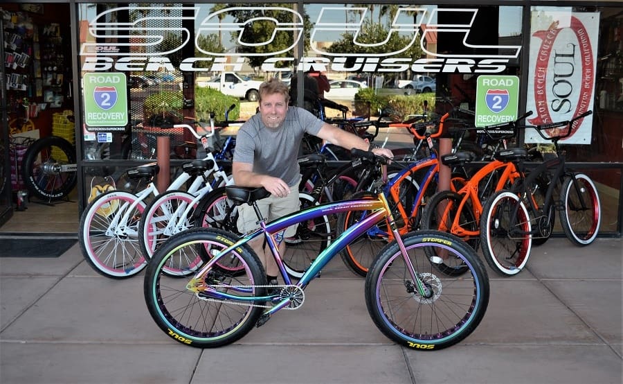 Man with colorful bicycle at bike shop.