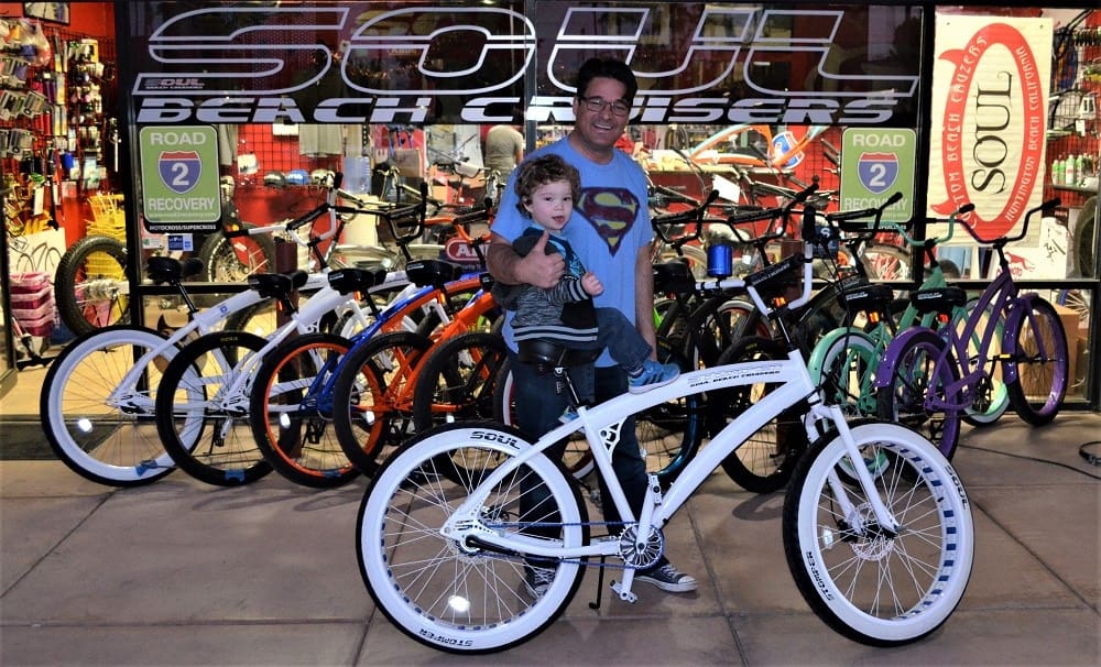Man and child with bicycles at store.