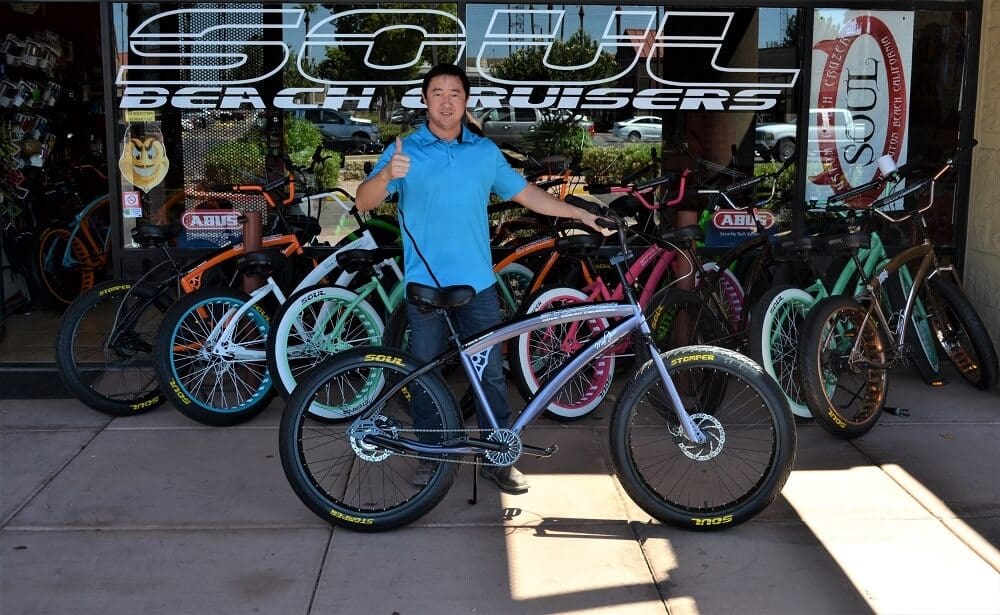 Man posing with bicycles outside store.