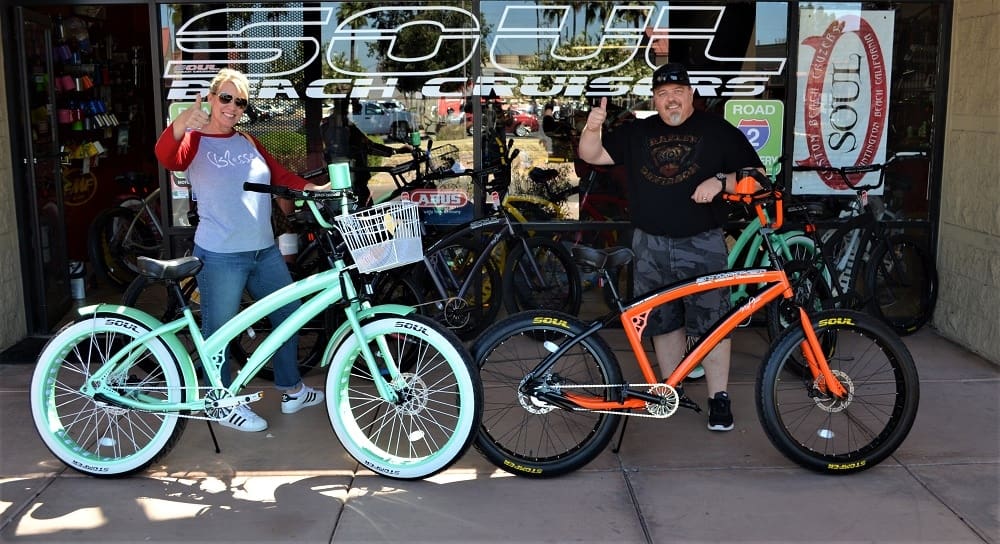 People posing with colorful beach cruiser bicycles.