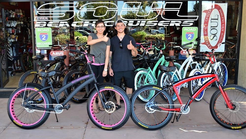 People posing with colorful beach cruisers.