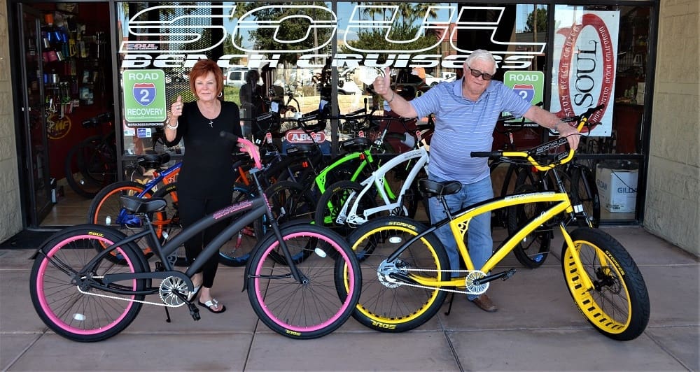 Two people posing with colorful bicycles.