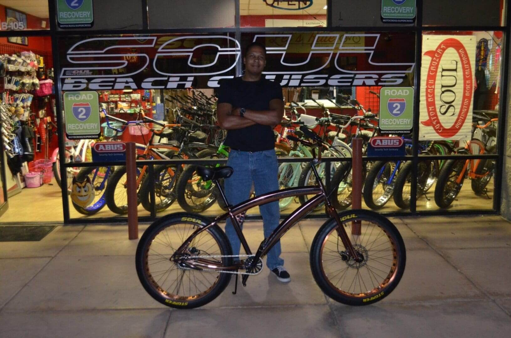 Man standing with bicycle outside bike shop.