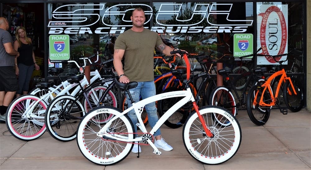 Man posing with white and red bicycle.