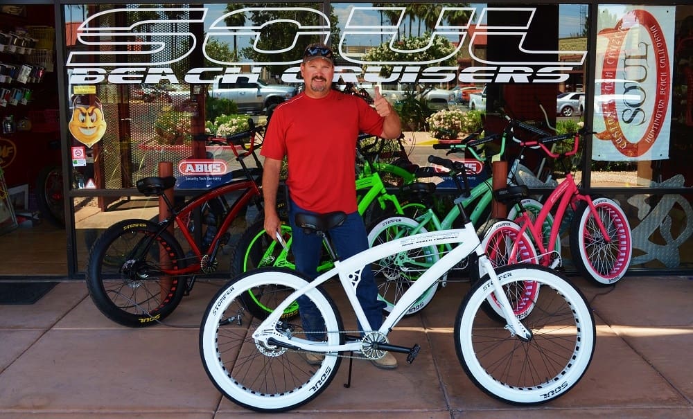 Man standing with colorful beach cruiser bikes.