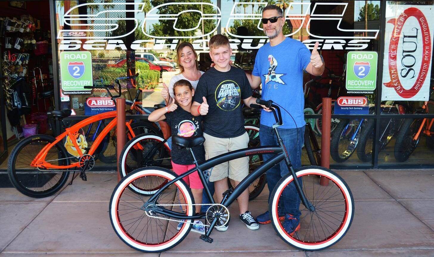 Family posing with bicycles outside a store.