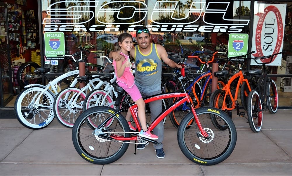 Man and girl with bicycles at store.