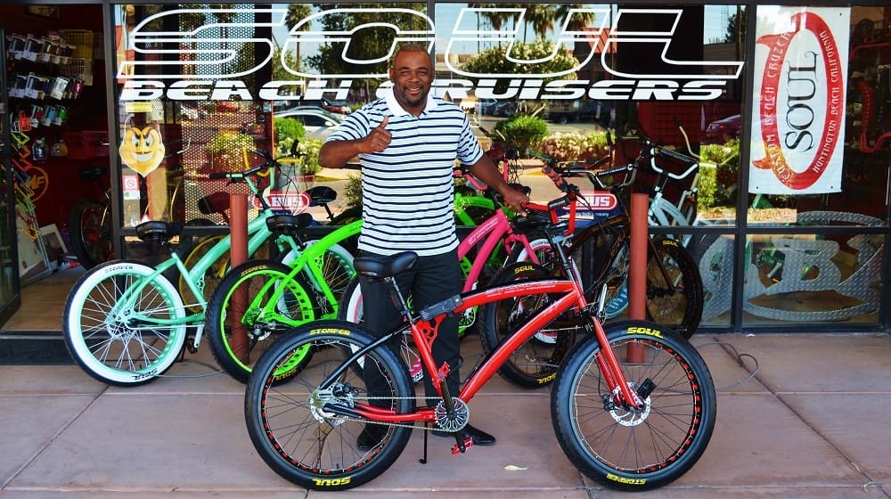 Man posing with colorful beach cruiser bikes.