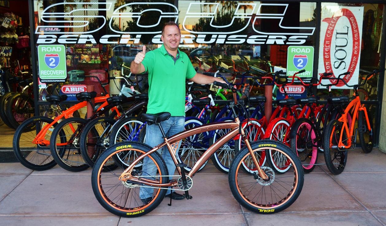 Man with bicycle in front of bike shop.