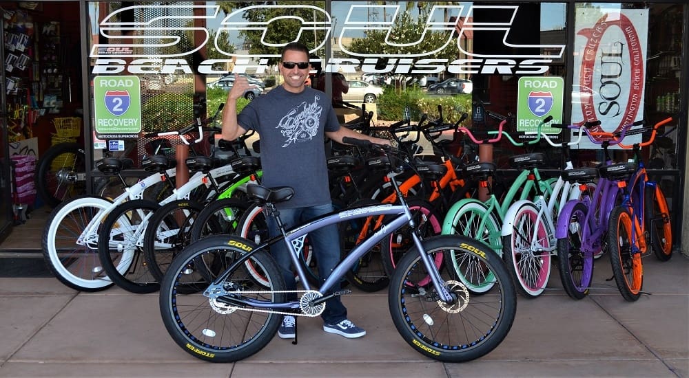 Man posing with bicycles outside Soul Beach Cruisers.