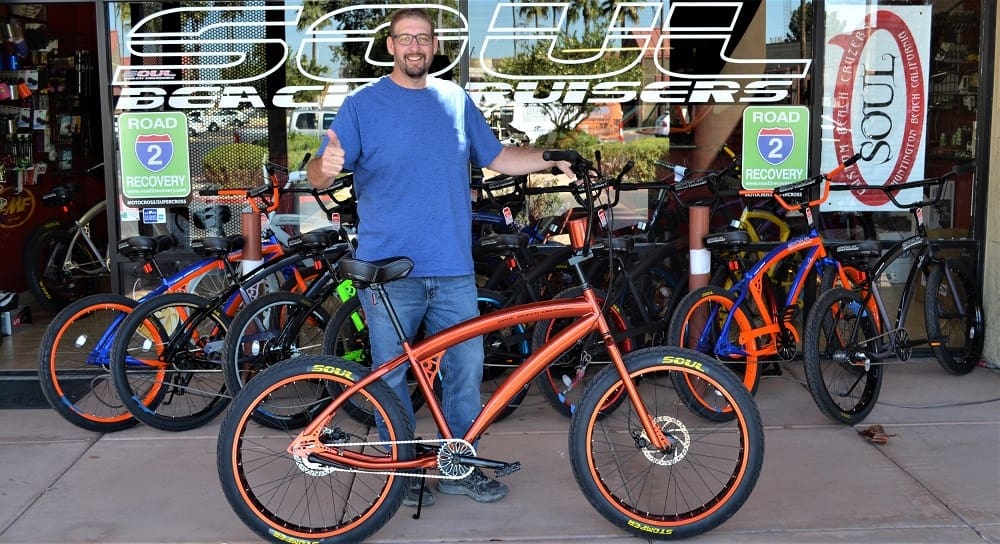 Man with bicycles outside a bike shop.