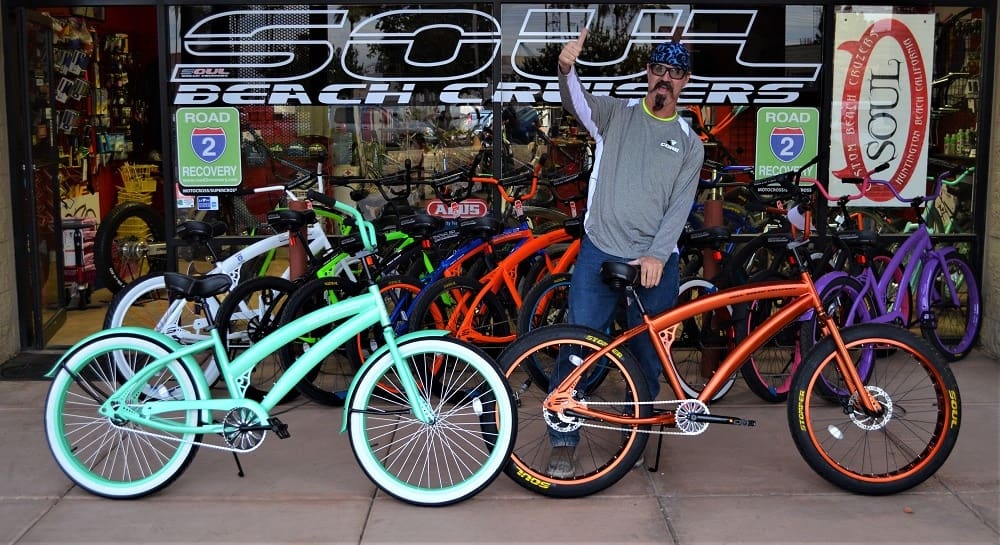Man posing with colorful beach cruiser bicycles.