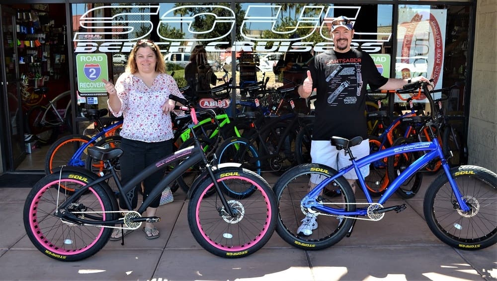 Two people with colorful beach cruiser bicycles.