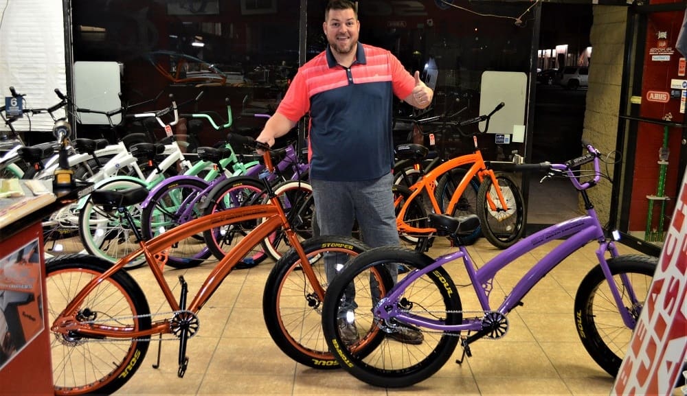 Man showcasing colorful bicycles in shop.