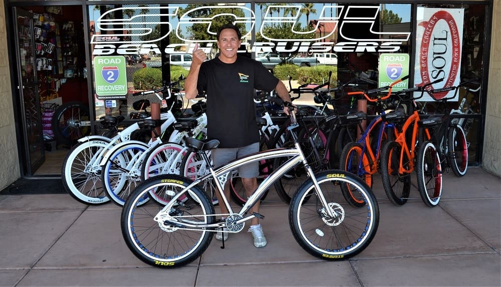 Man holding a bicycle outside a shop.