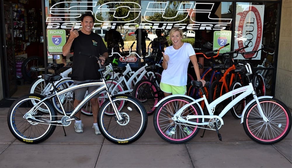Two people with cruiser bicycles outside shop.