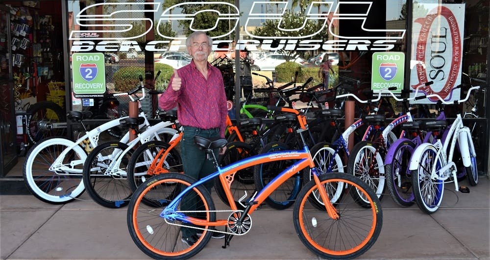 Man standing with colorful beach cruiser bicycles.