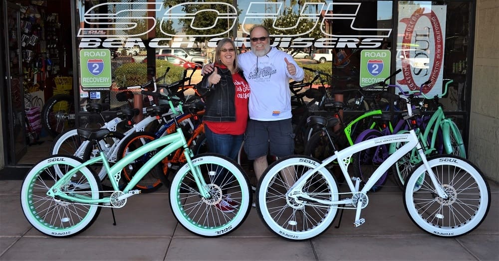 Couple standing with bicycles outside a shop.