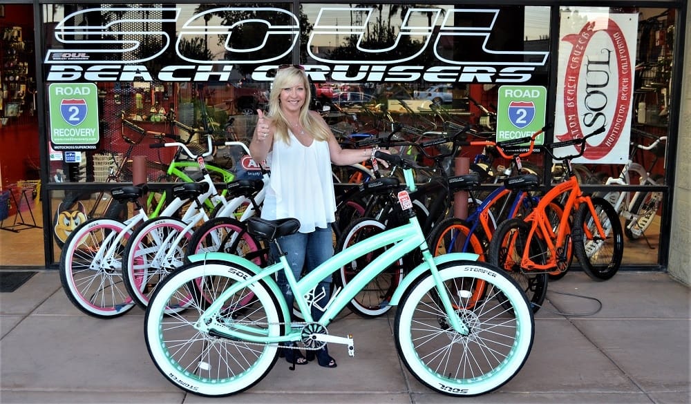 Woman with bicycle in front of shop.
