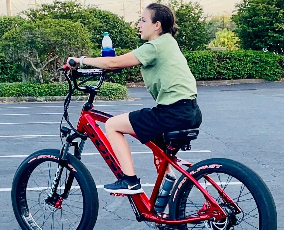 Person riding a red bicycle in parking lot.
