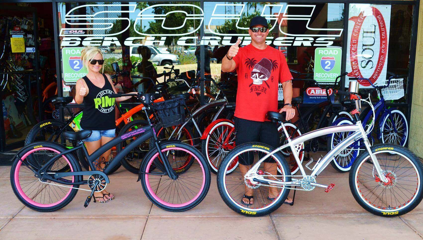 Two people with bicycles outside bike shop.