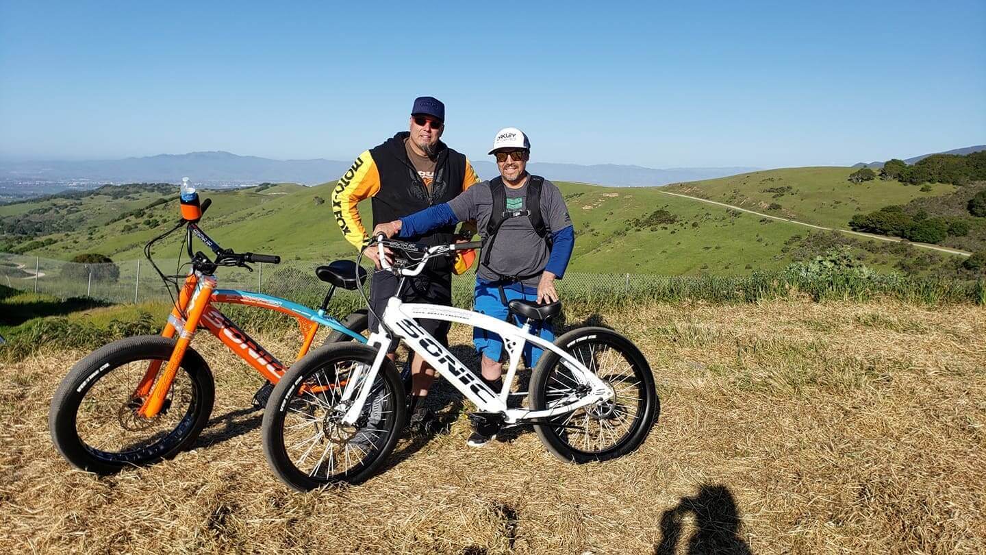 Two people with bikes on hillside.