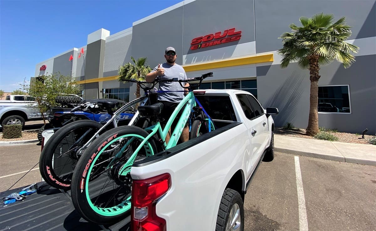 Man loading bicycles onto white pickup truck.