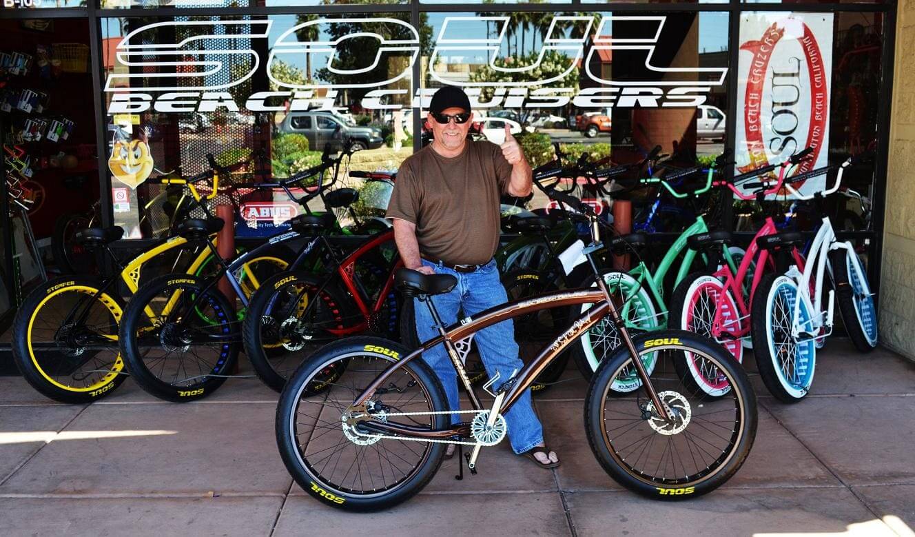 Man standing with bicycles outside bike shop.