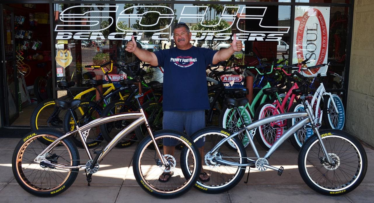 Man with bicycles in front of bike shop.