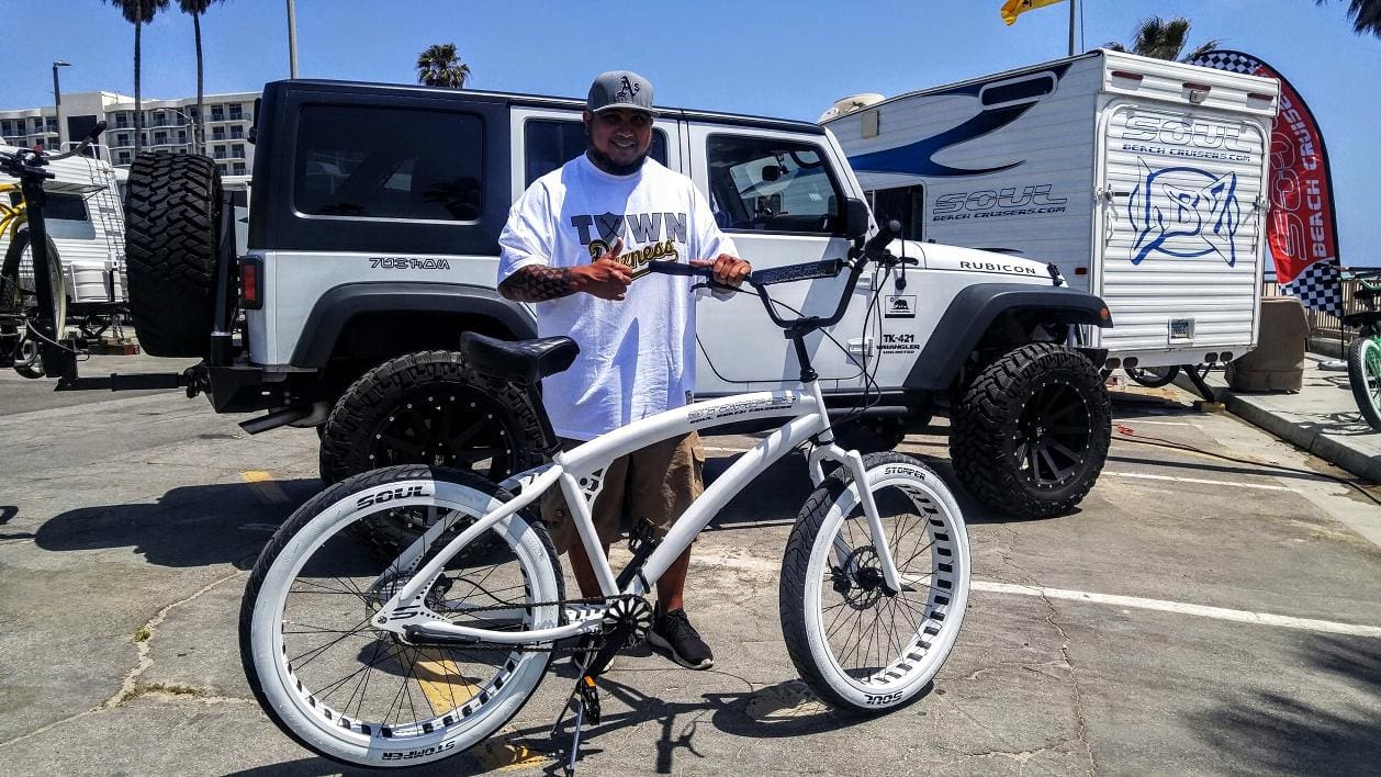 Man holding bicycle near a large vehicle.