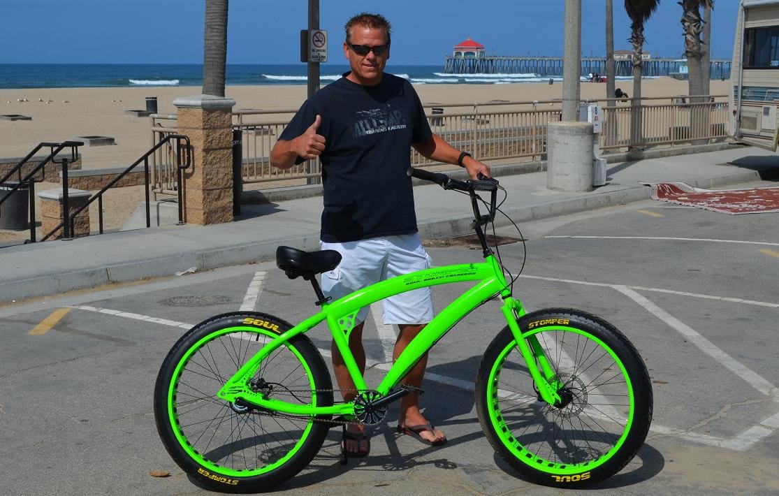 Man with green bicycle at the beach.