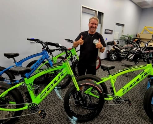 Man smiling with thumbs up near bicycles.