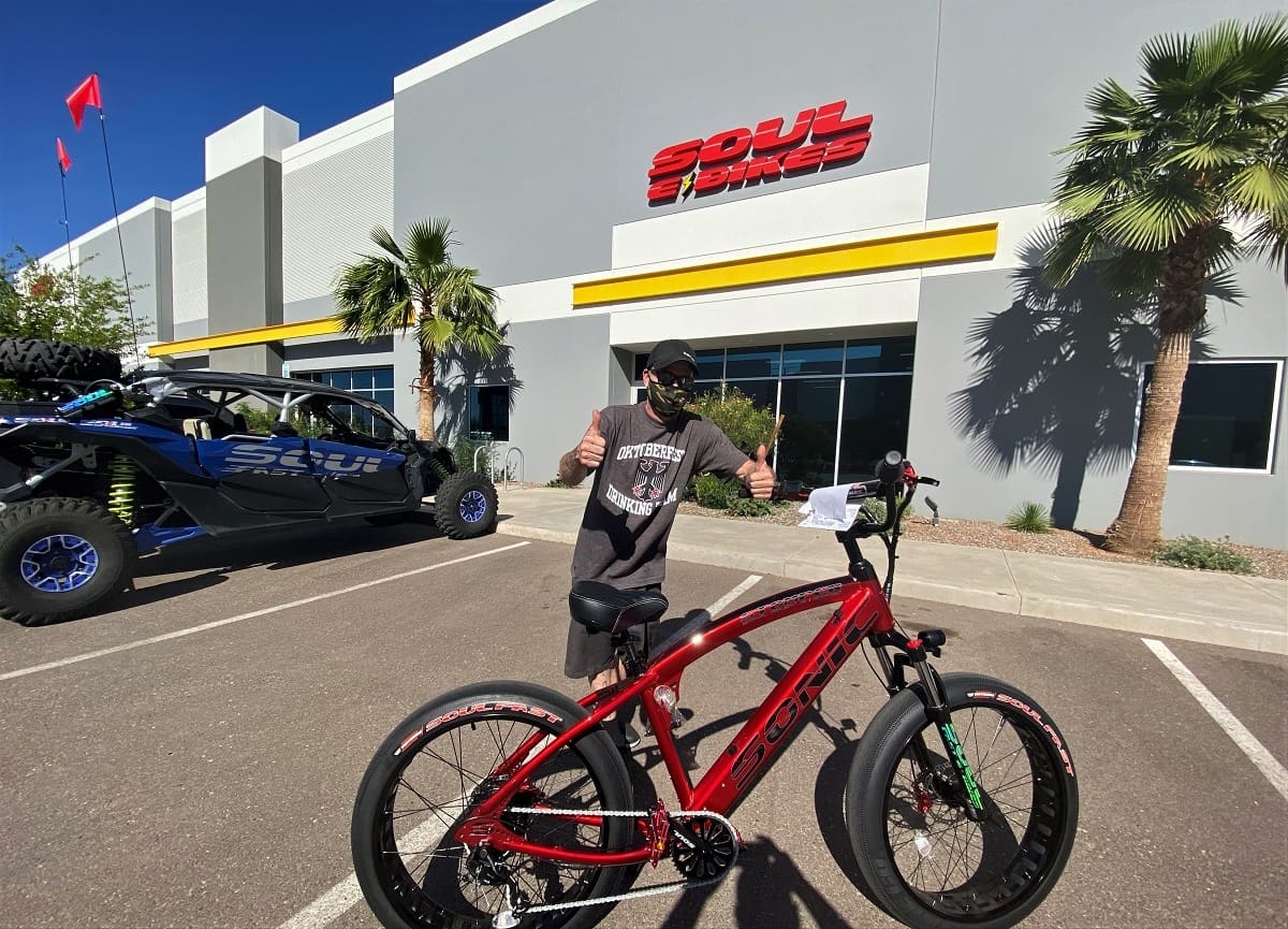 Person with red bicycle outside Soul Bikes store.