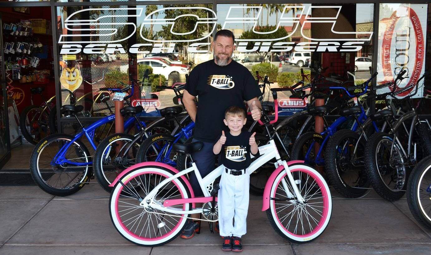 Man and child with pink bicycle outside shop.