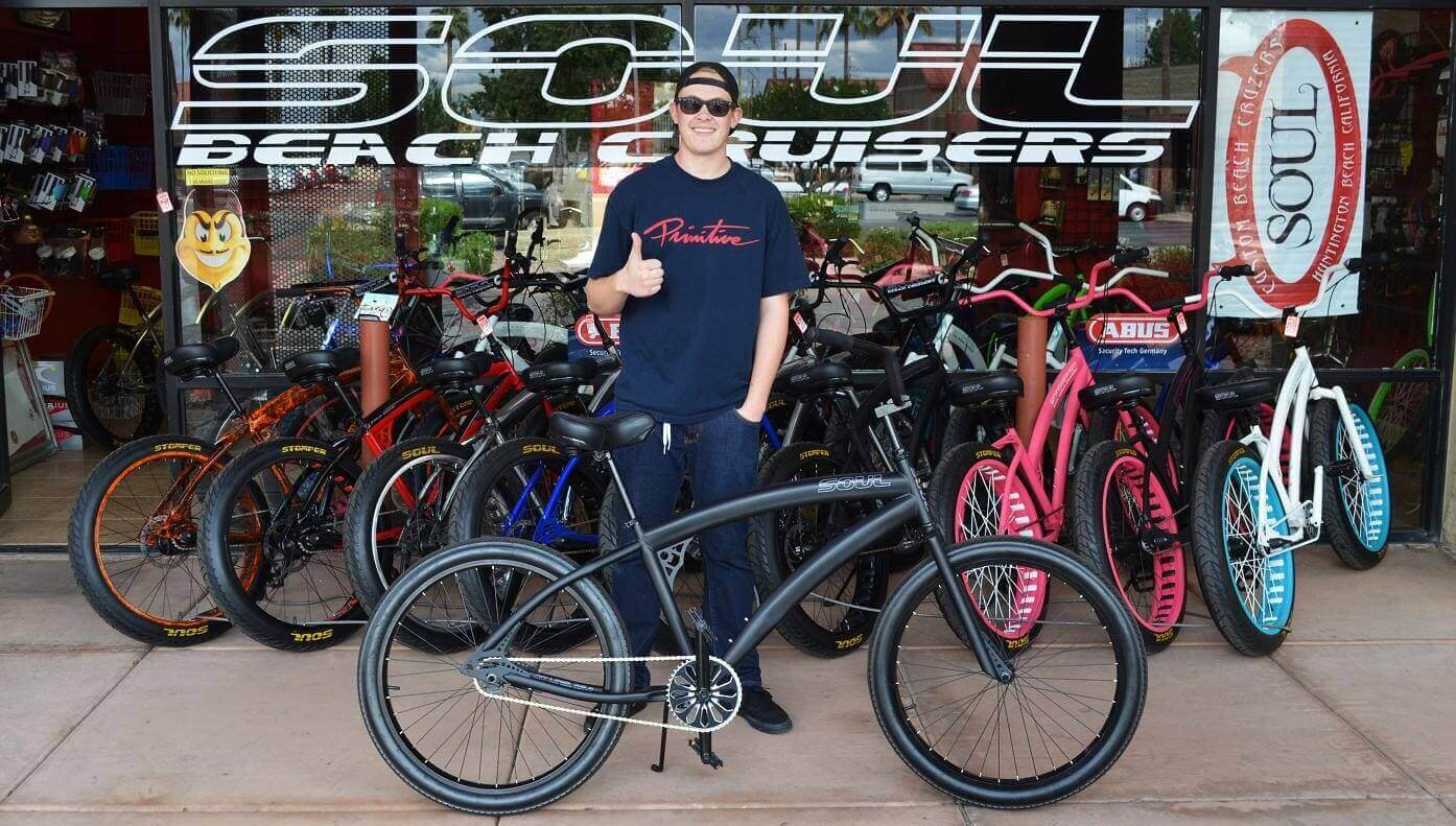 Person with bicycle in front of shop.