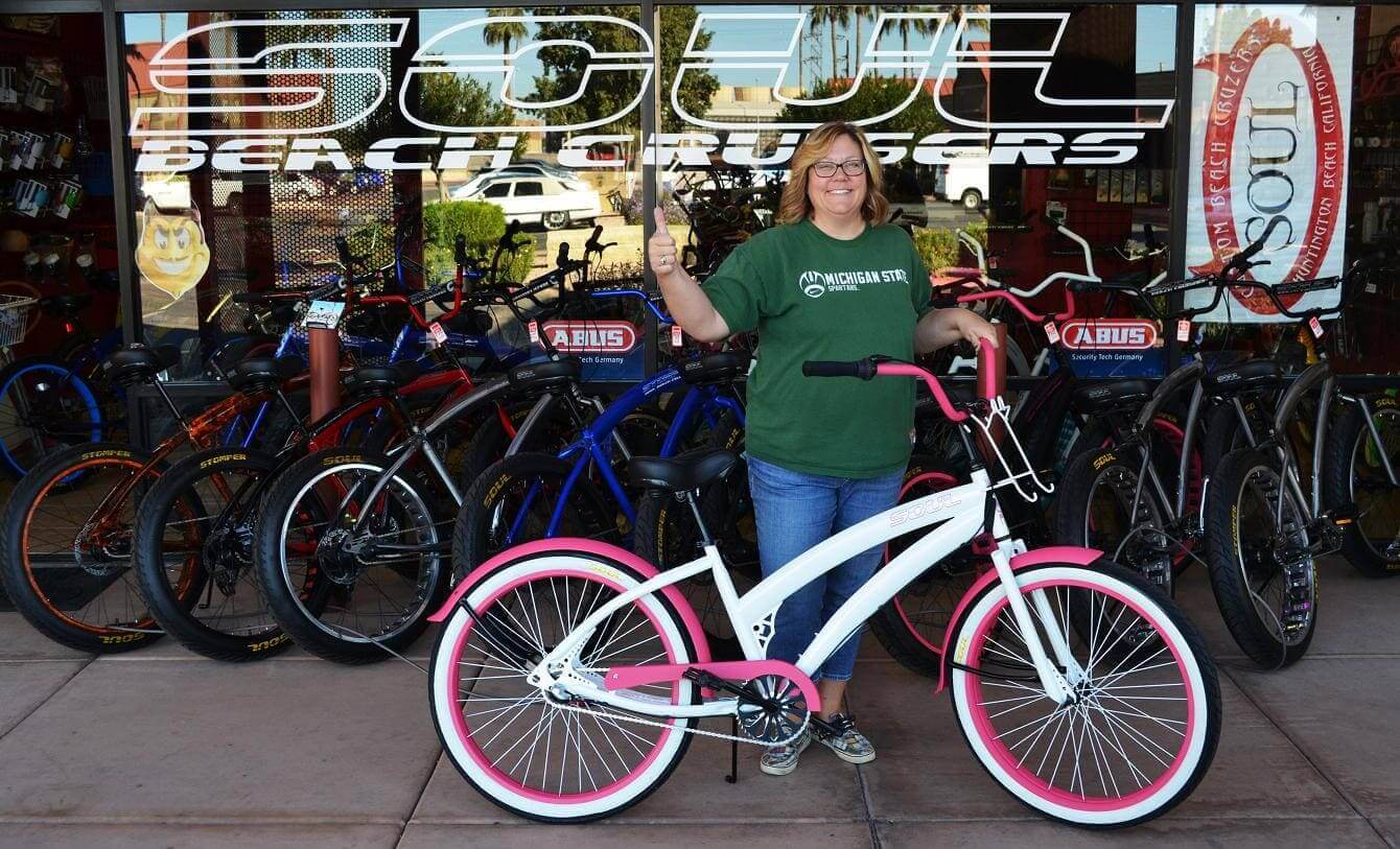 Person with bicycle in front of bike shop.