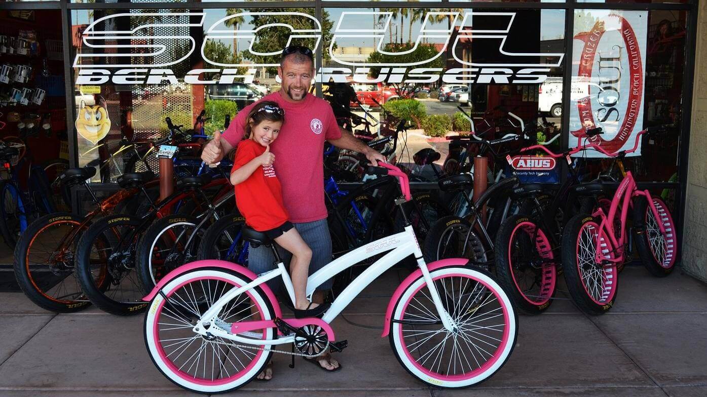 Man and child with white and pink bicycle.