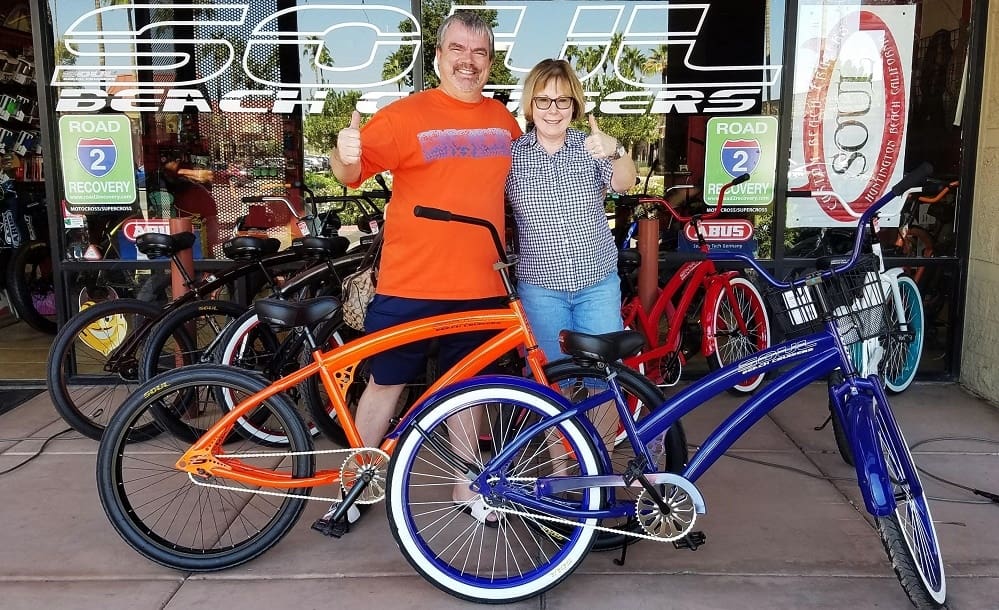 Two people posing with colorful bicycles.