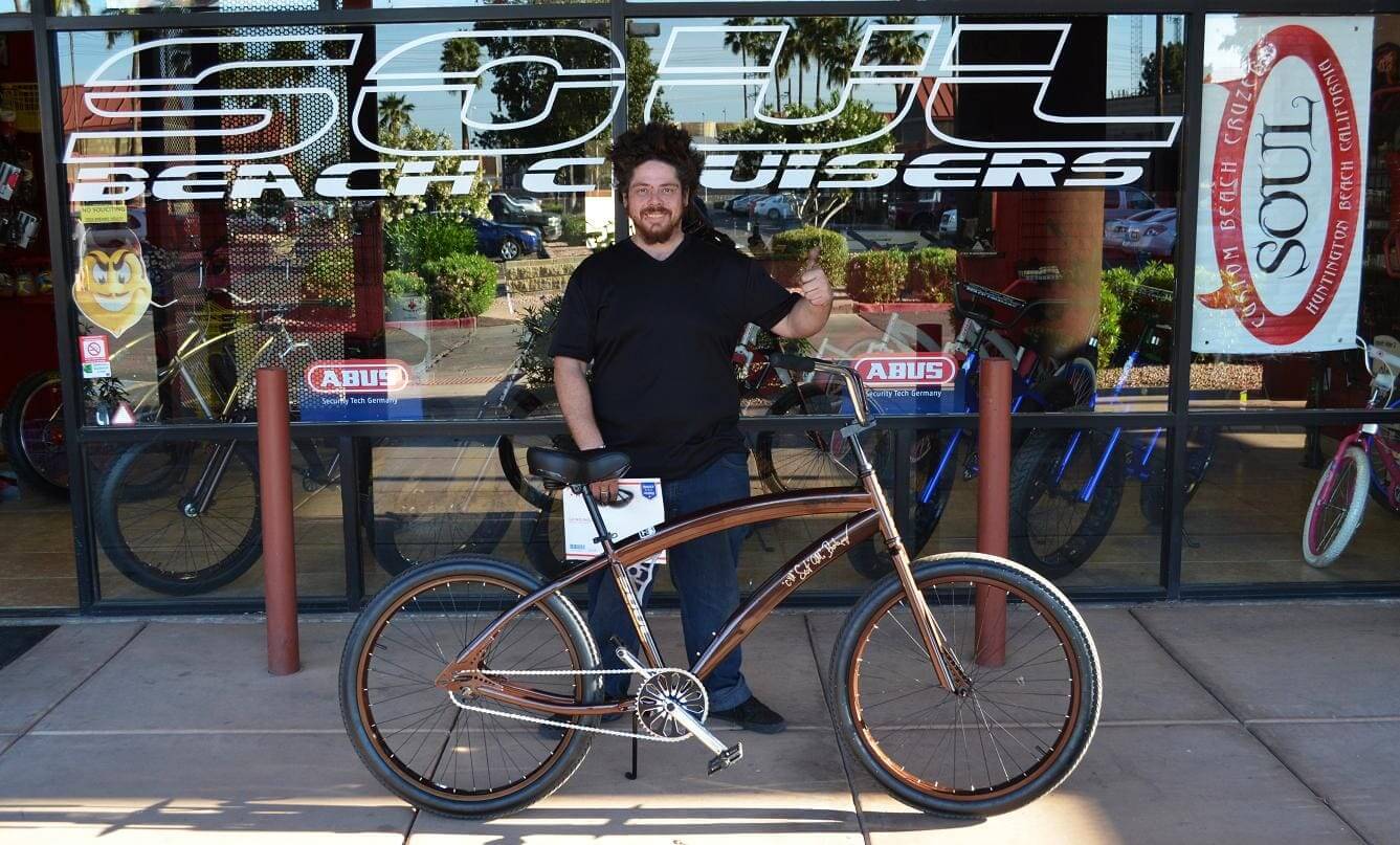 Man standing with a bicycle outside store.