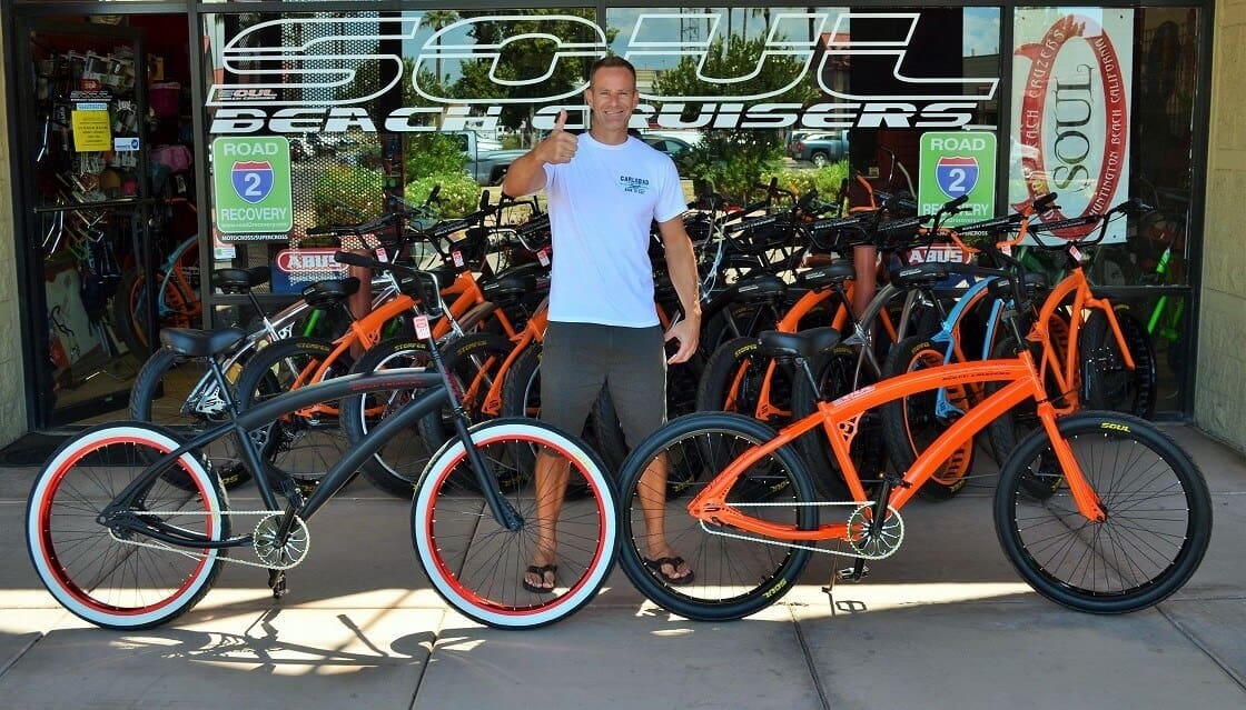 Man standing with two custom bicycles.