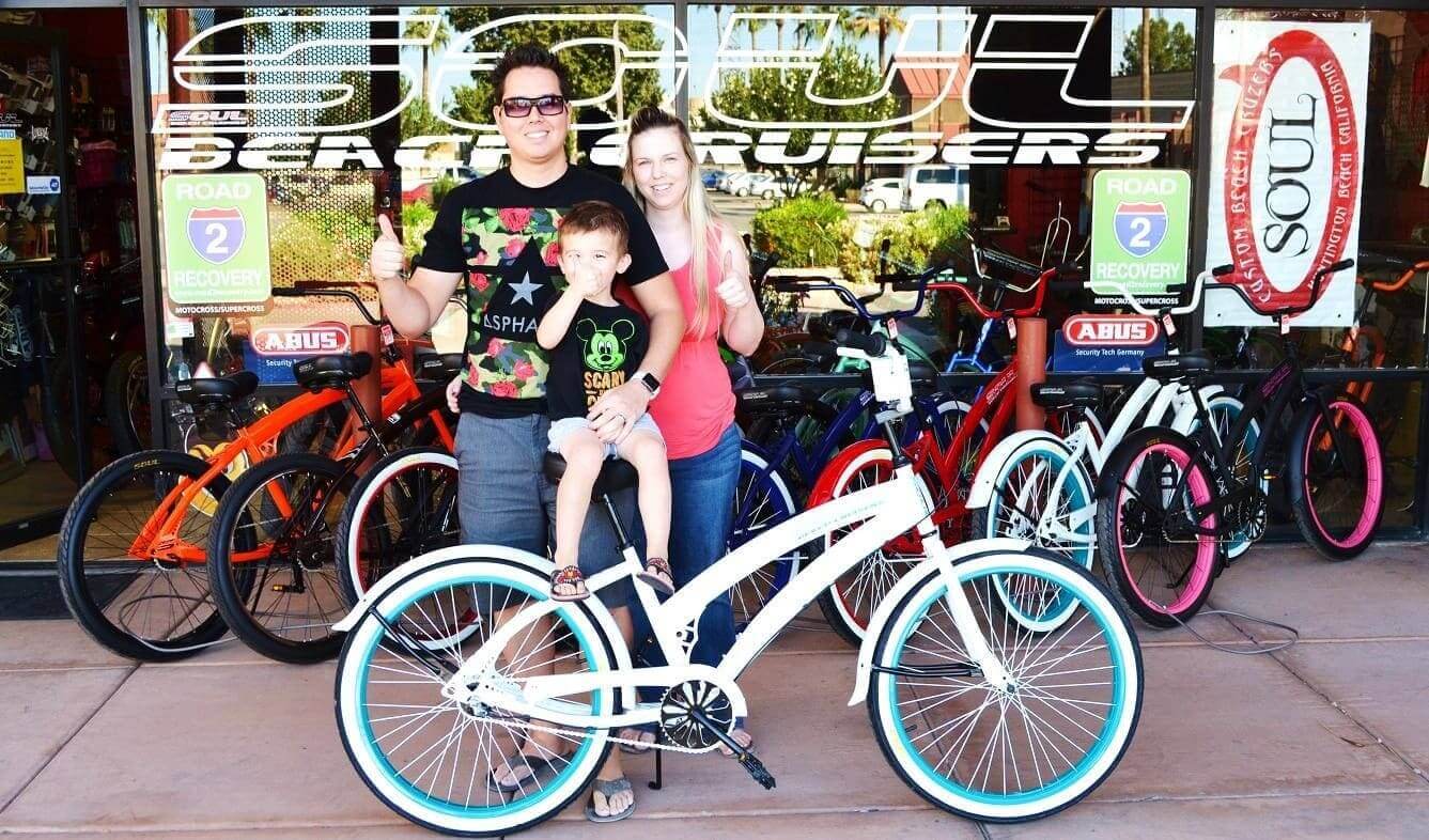 Family posing with bicycles outside bike shop.
