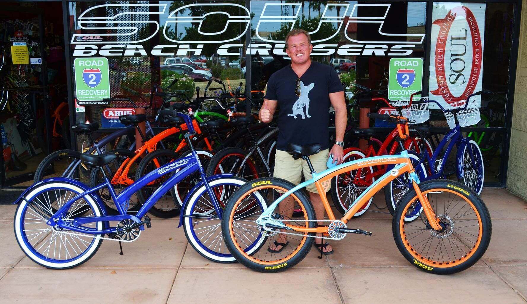 Man standing with colorful beach cruiser bicycles.