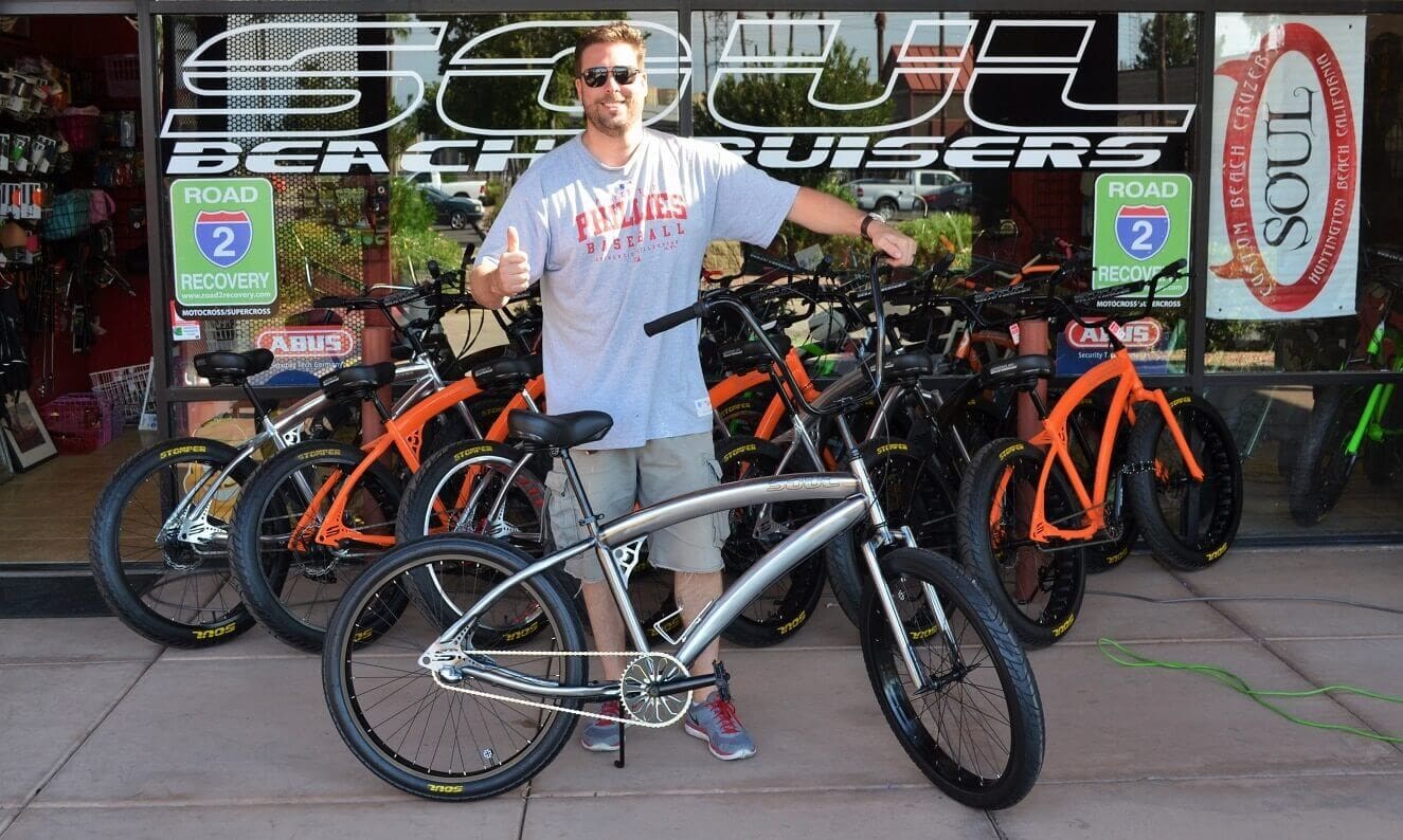 Man posing with a cruiser bicycle.