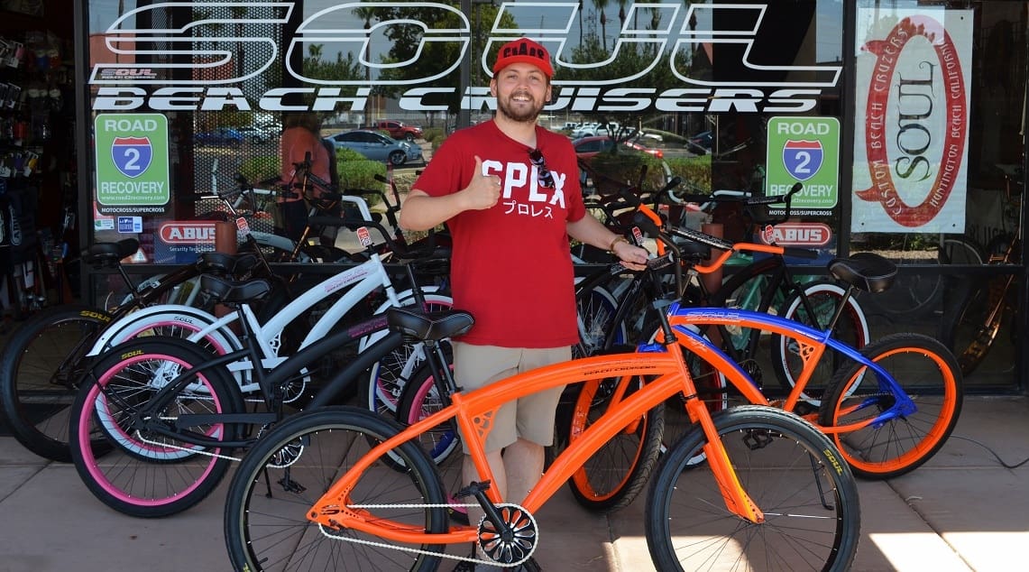 Man standing with colorful beach cruisers.