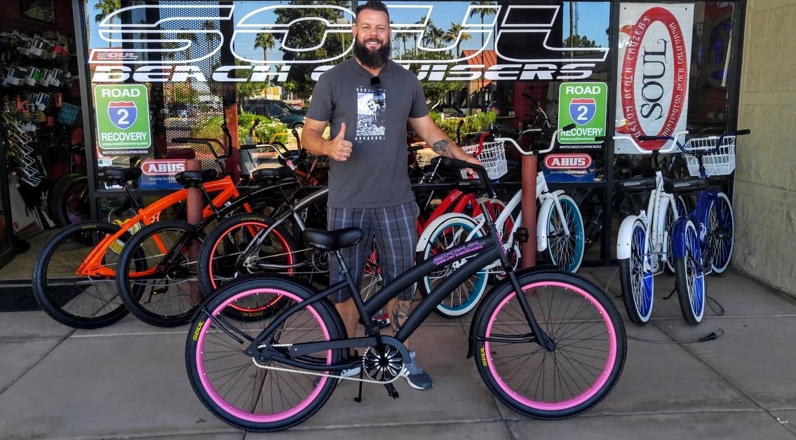 Man with bicycle in front of bike shop.
