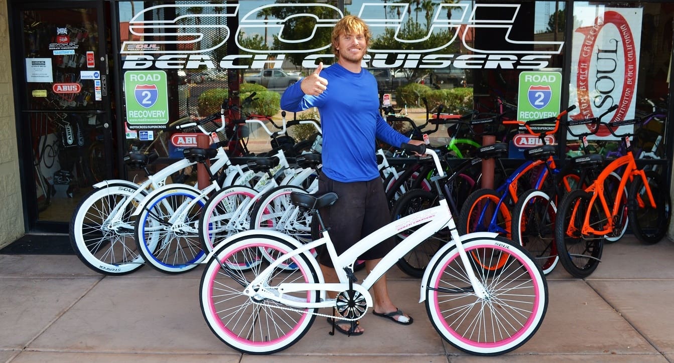 Man posing with white beach cruiser bicycle.
