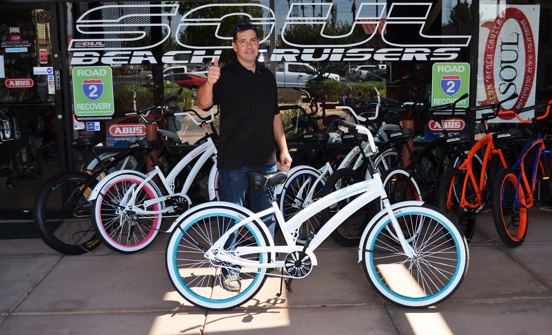 Man holding a white bicycle outside store.