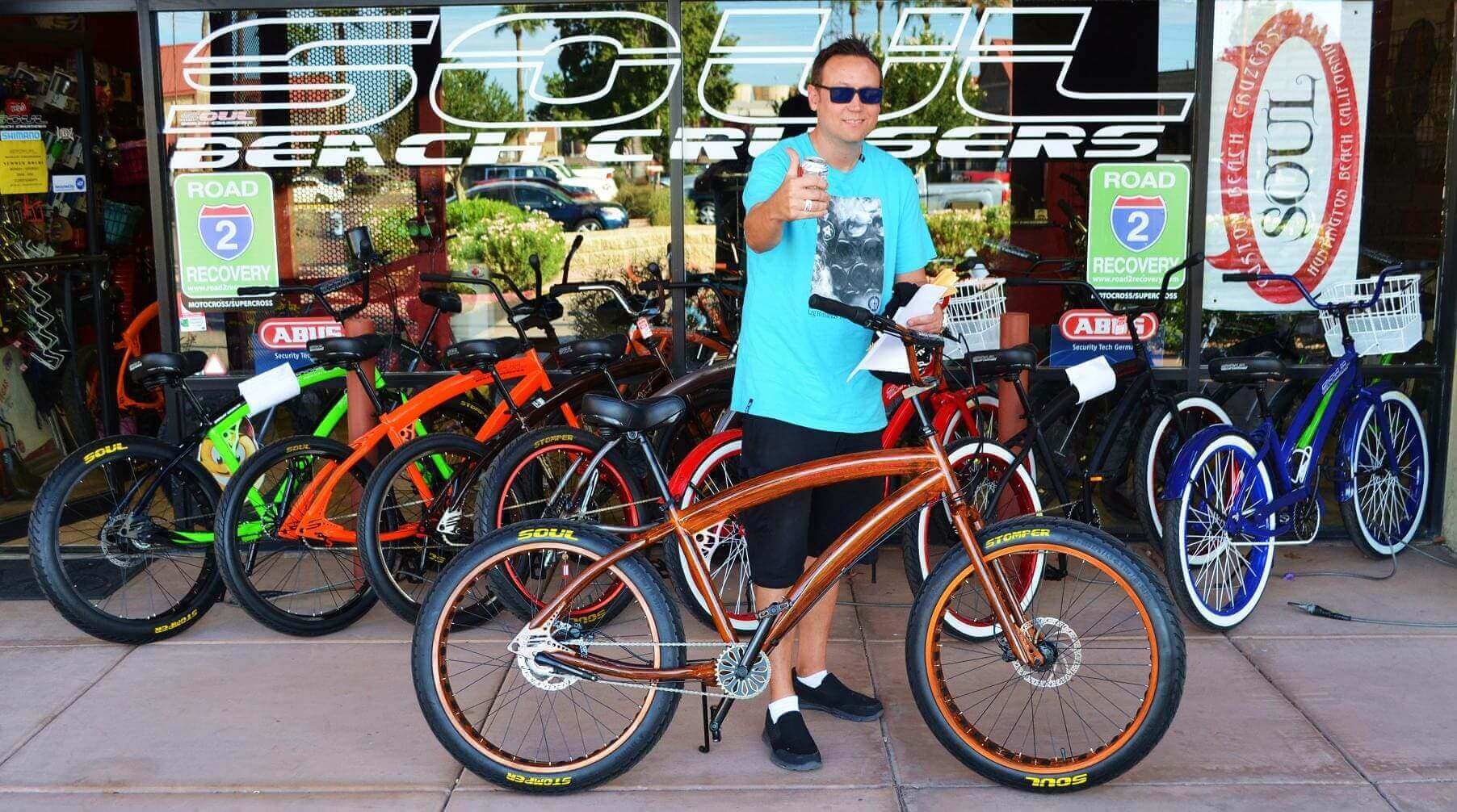 Man posing with bicycles outside a shop.
