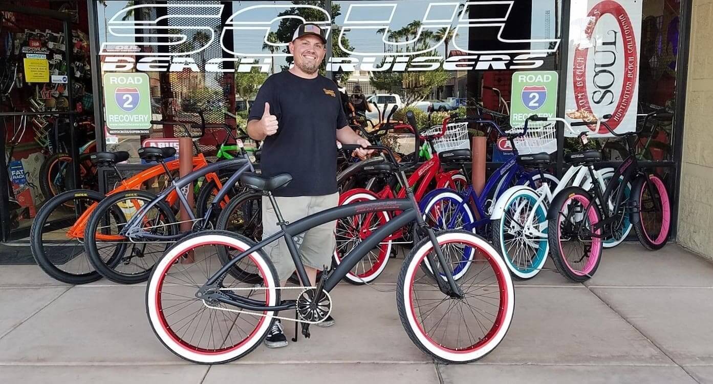 Man with bicycle outside bike shop.